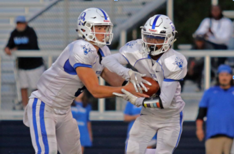 Senior Bo Kite hands the ball off to Senior Miles Ellis in a football game last year at Atlee.