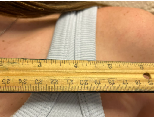 A student measures her shoulder straps to see if they meet dress code requirements.