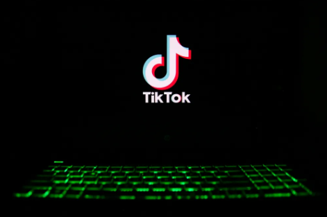 The TikTok logo displayed on a screen above a glowing green keyboard. 