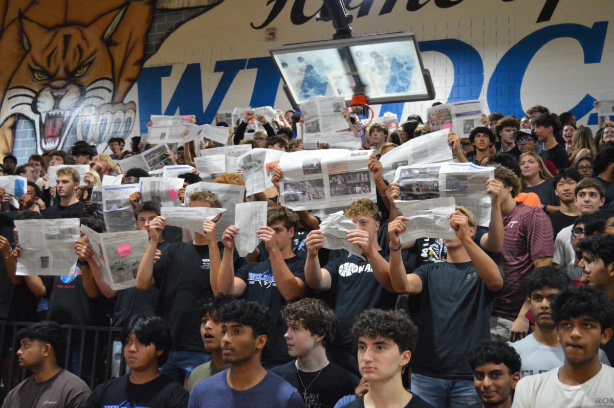 Wildcats read and hold up the Deep Run Sentinel during pep rally.