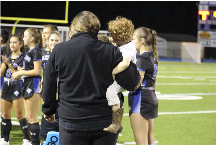 Rachel Haislip holds her son while coaching varsity Field Hockey in their game against Matoaca.
